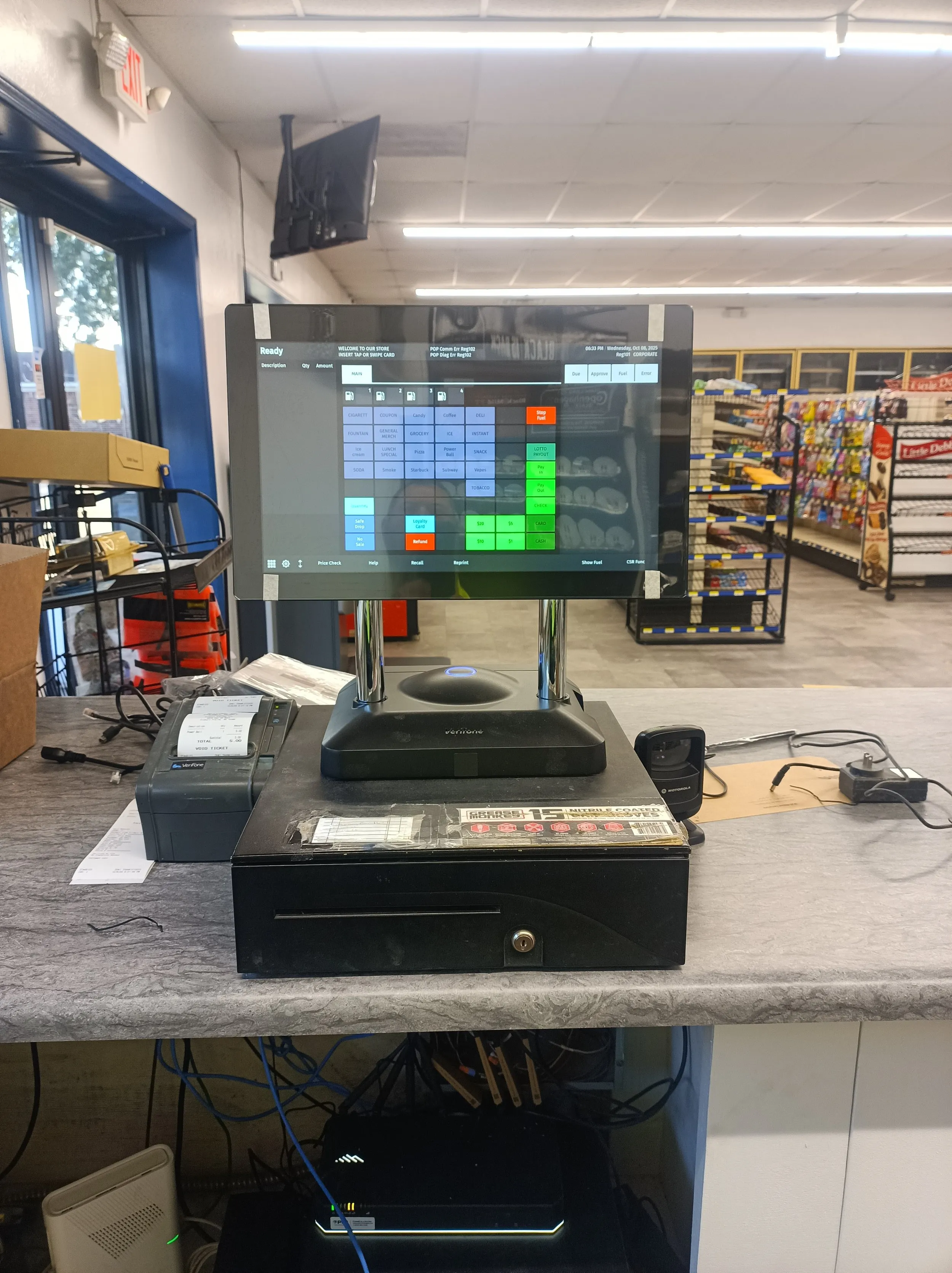 A point-of-sale touchscreen terminal and cash drawer installed on a convenience store checkout counter.